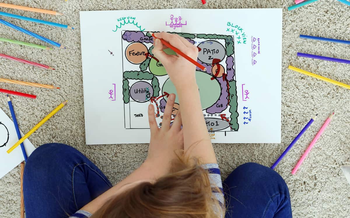 woman drawing a garden plan with colored pencils