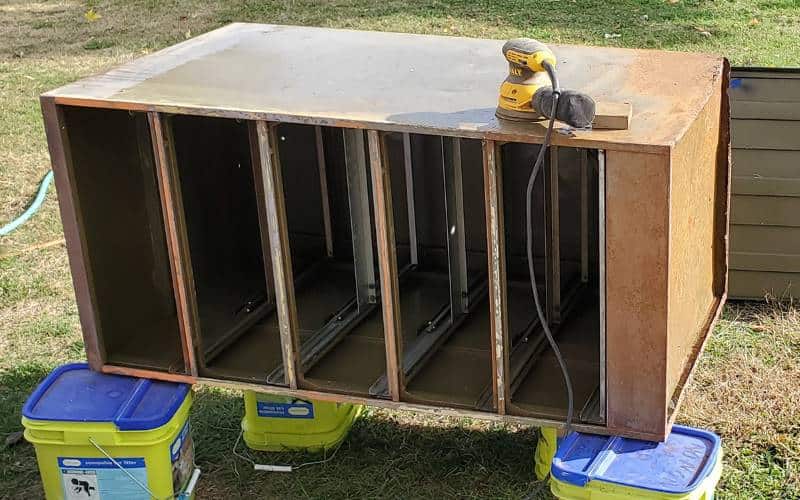 Filing cabinet on it's side with orbit sander on top