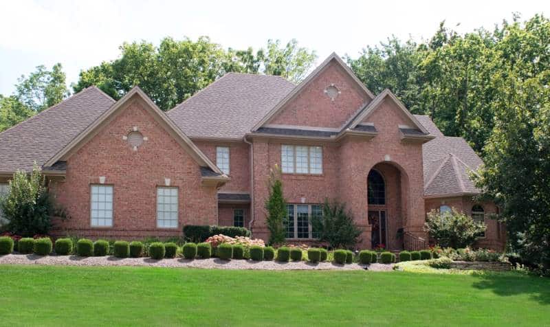 small evergreen shrubs in front of a large house